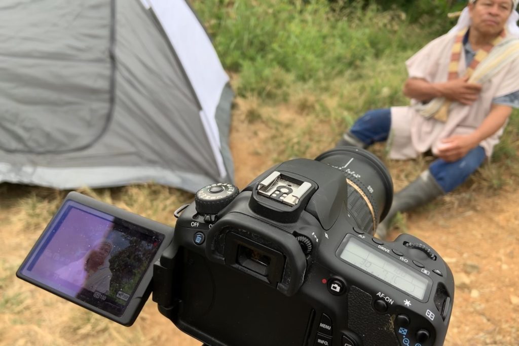 Close up of a camera shooting a subject sitting on the ground