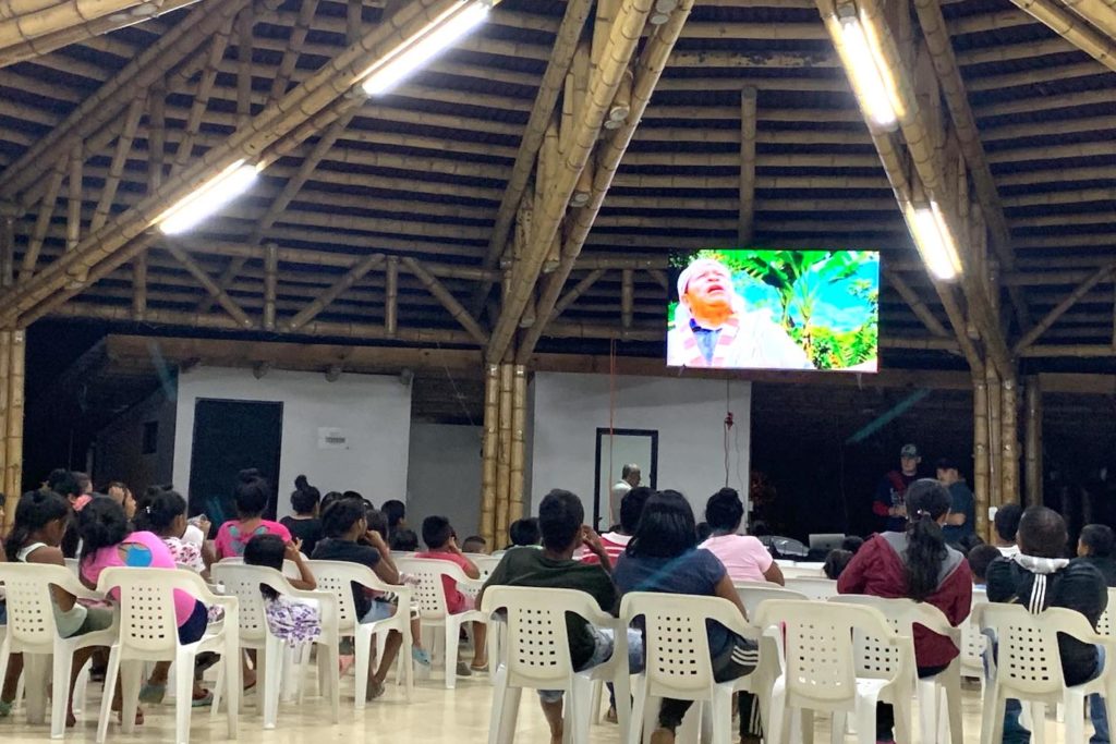 A group of people watching a video on a TV in a large room