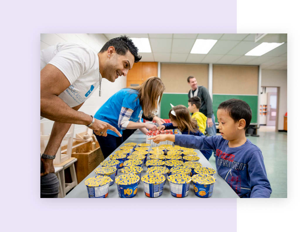 A Backpack Buddies staff member helping a child pick out food items.